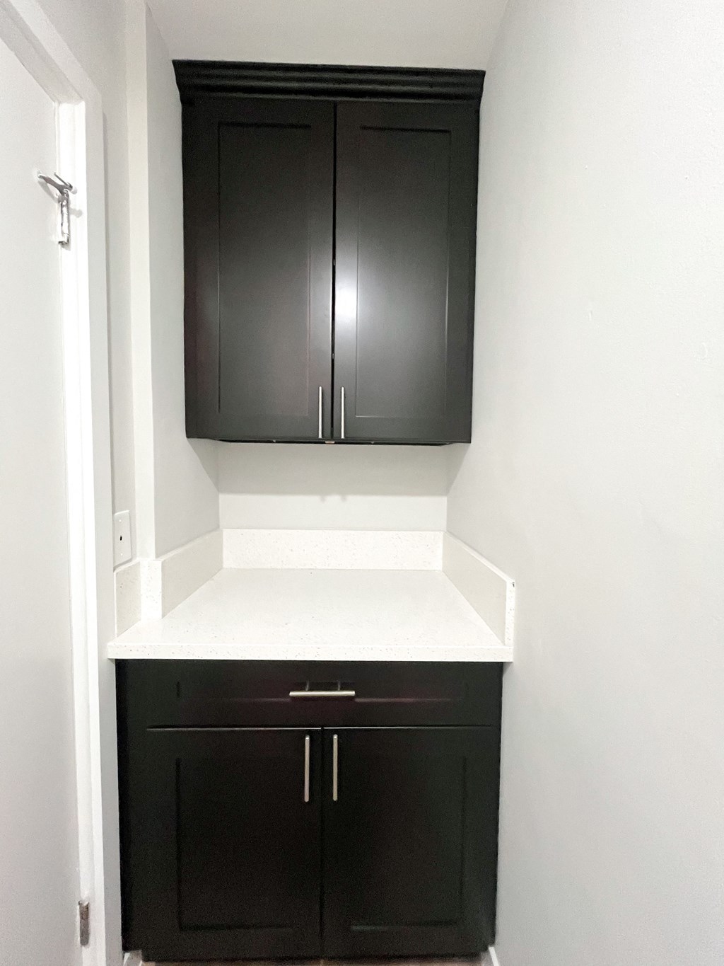 a small kitchen with black cabinets and white counter top and a cabinet