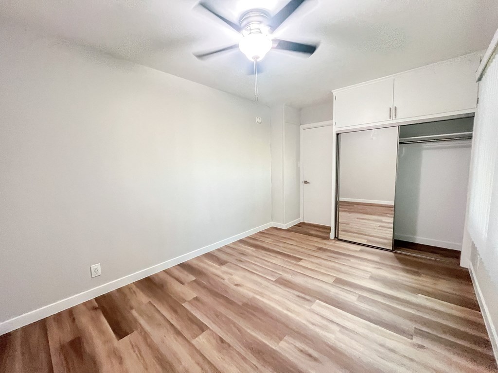 an empty living room with wood flooring and a closet