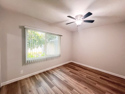the spacious living room of a home with wood flooring and a ceiling fan