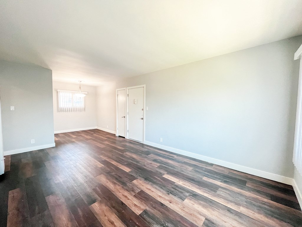 an empty living room with wood floors and white walls