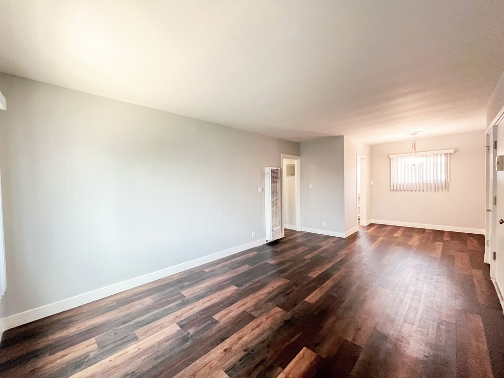 an empty living room with wood flooring and white walls