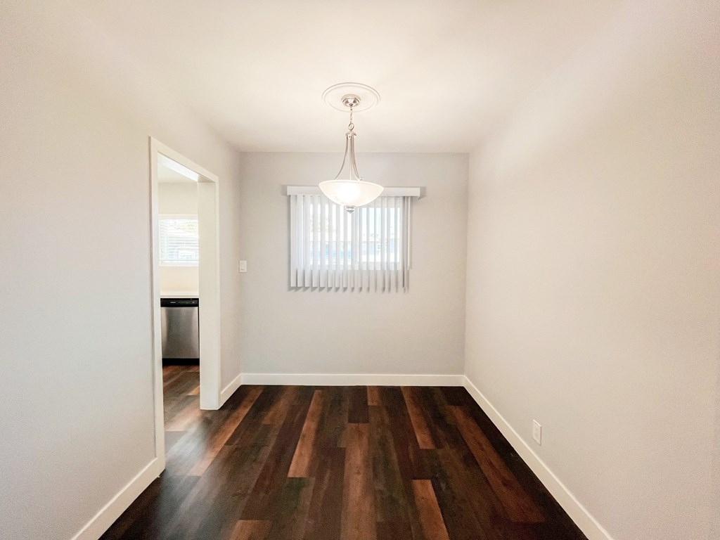 an empty living room with hard wood flooring and a window