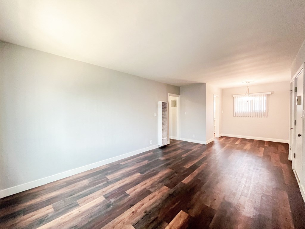 an empty living room with wood floors and white walls