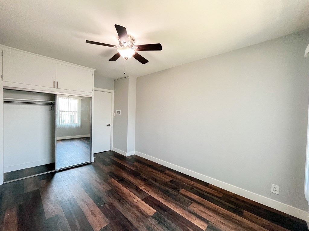 an empty living room with hard wood floors and a ceiling fan