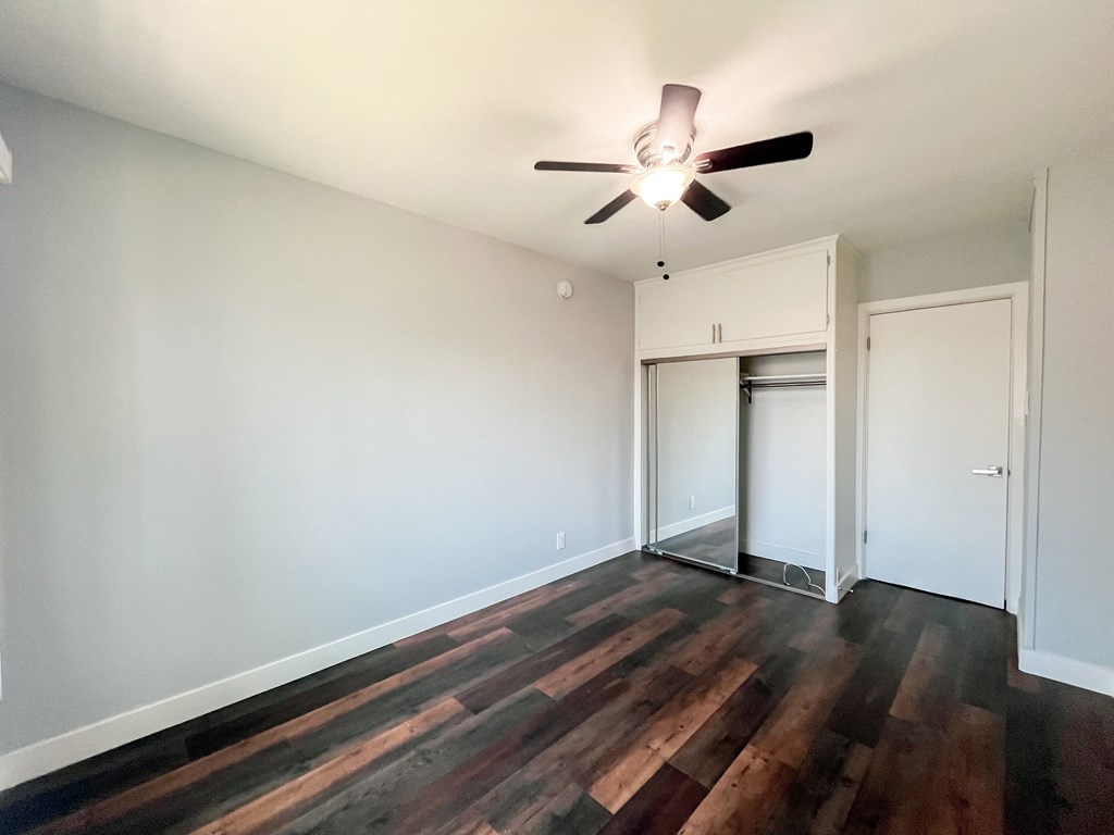an empty living room with hard wood floors and a ceiling fan