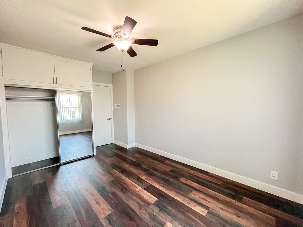 an empty living room with wood flooring and a ceiling fan
