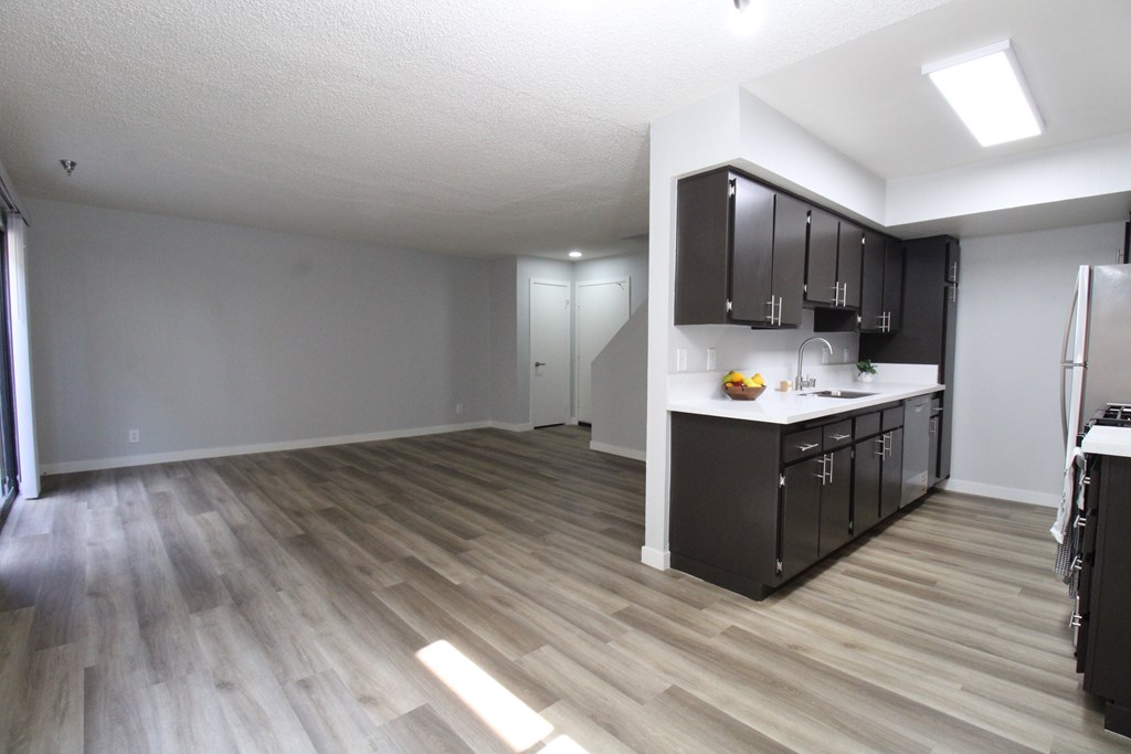 A kitchen with black cabinets and a wooden floor.