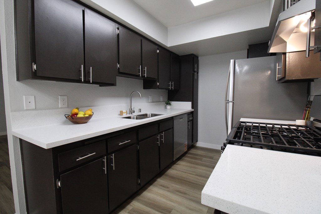 A kitchen with black cabinets and a white countertop.