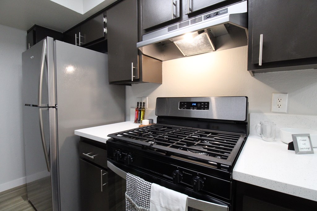 A modern kitchen with a stainless steel refrigerator and a black stove top oven.