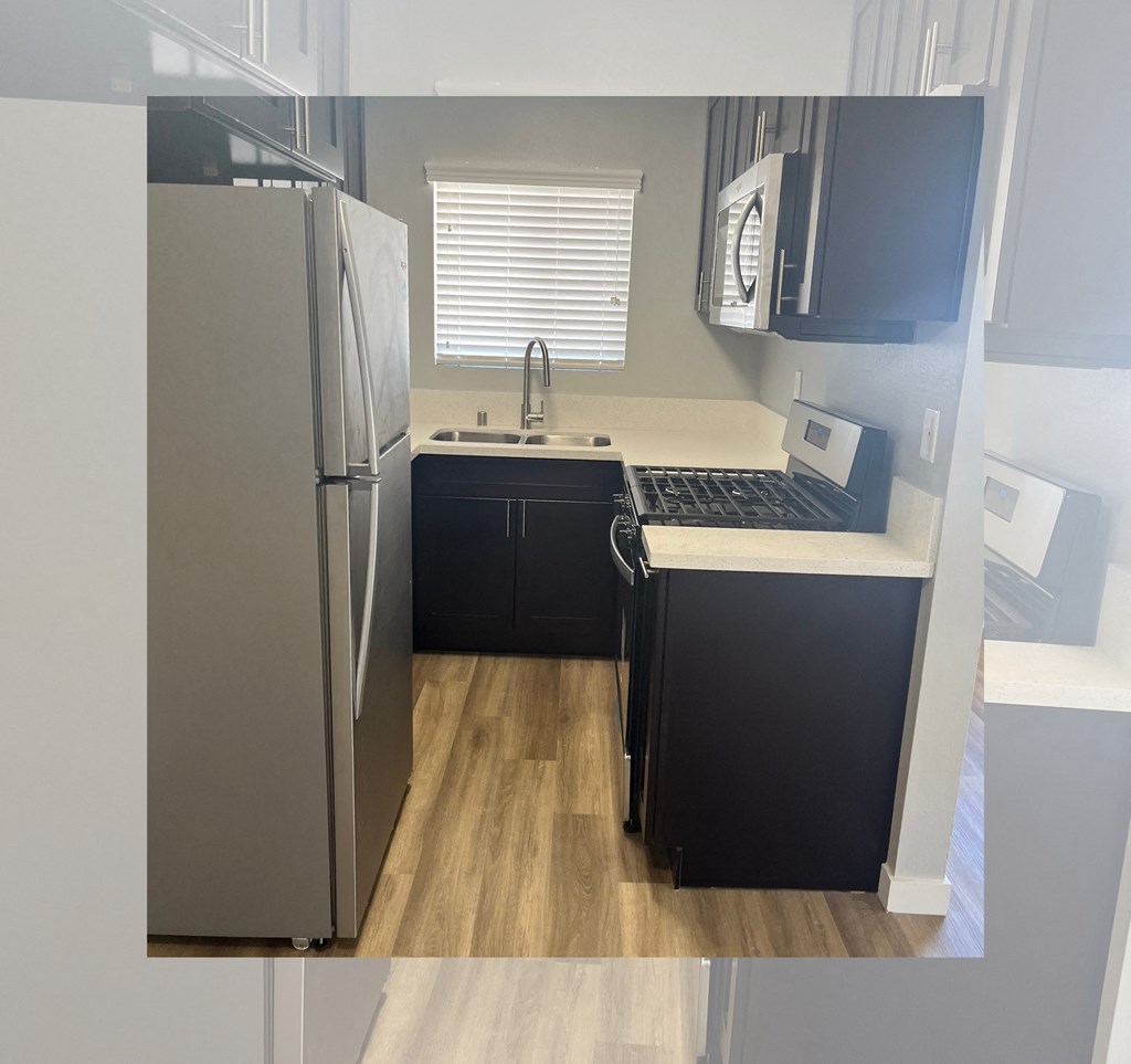 A kitchen with a refrigerator, sink, and cabinets.