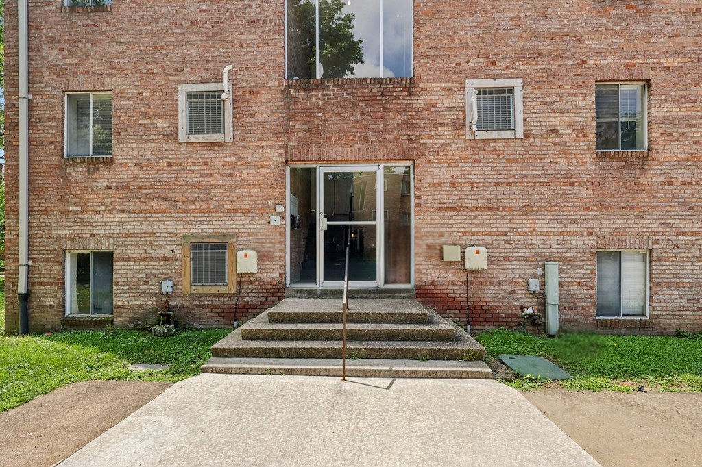 A brick building with a set of stairs leading to a glass door.