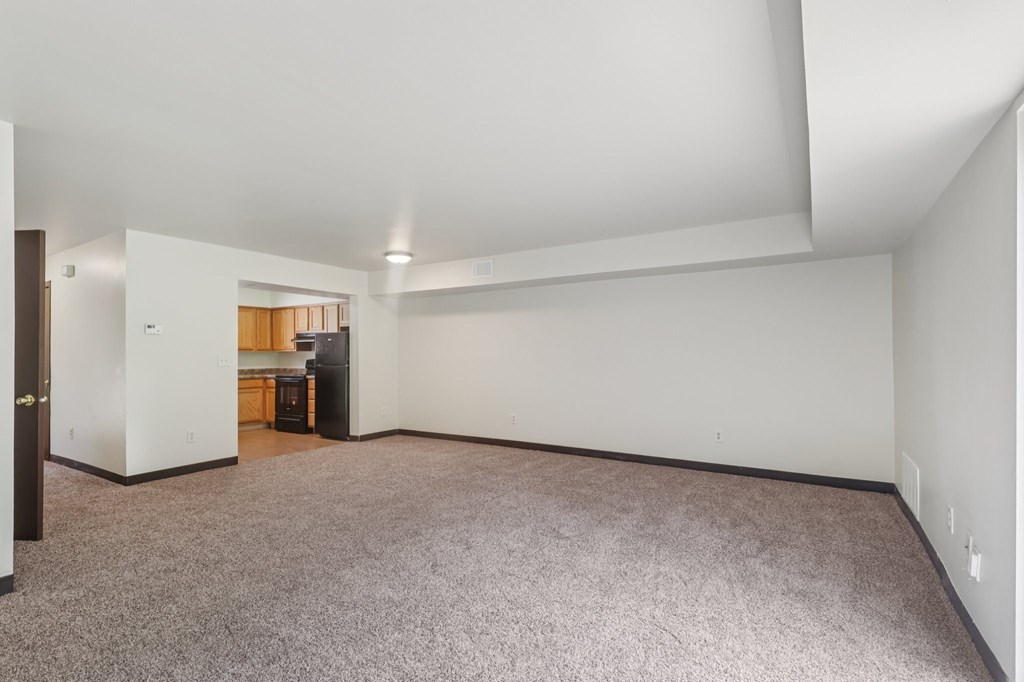 A large empty room with a carpeted floor and white walls.