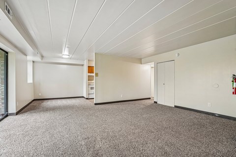 A spacious room with a carpeted floor and white walls.