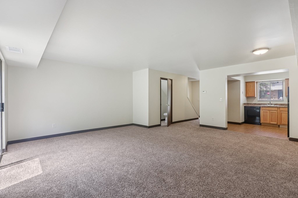 A spacious room with a carpeted floor and white walls.