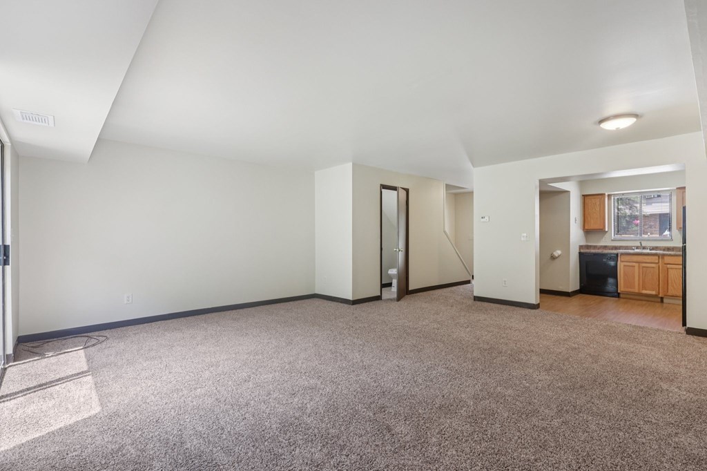 A spacious room with a carpeted floor and white walls.