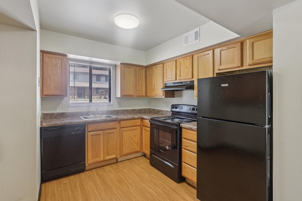 A kitchen with black appliances and wooden cabinets.