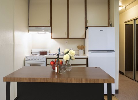 A kitchen with a table in front of a stove and a refrigerator.
