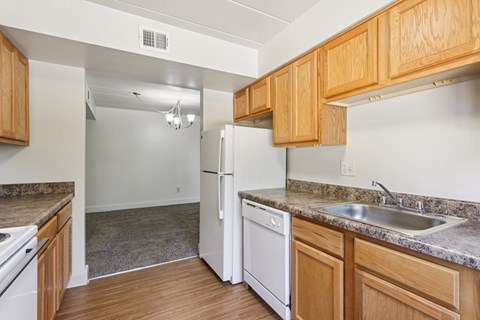 A kitchen with a white refrigerator and wooden cabinets.