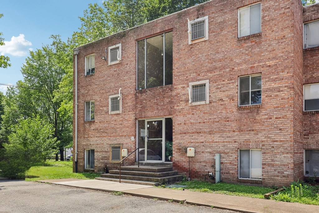 A red brick building with a tree in front.
