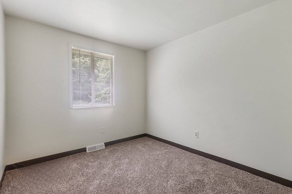 A room with a window and carpeted floor.