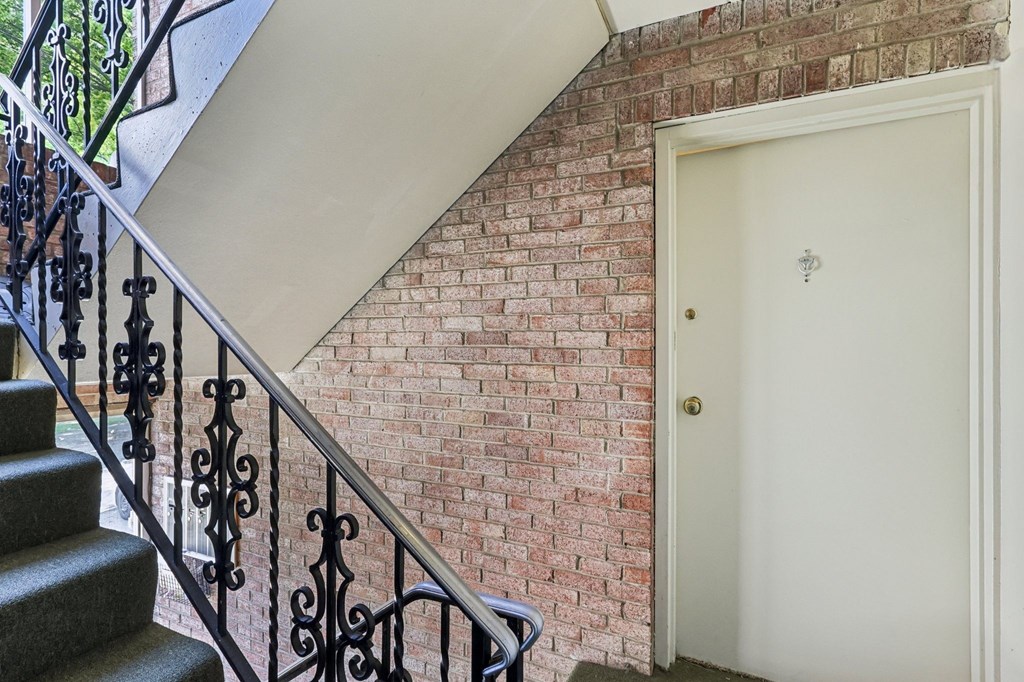 A white door is on the right side of a brick wall.