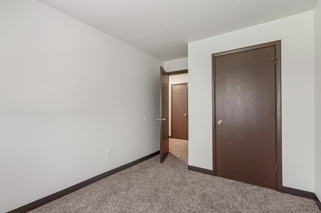 A room with a brown door and a carpeted floor.