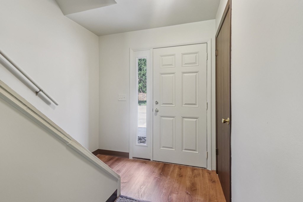 A white door is in a hallway with a wooden floor.