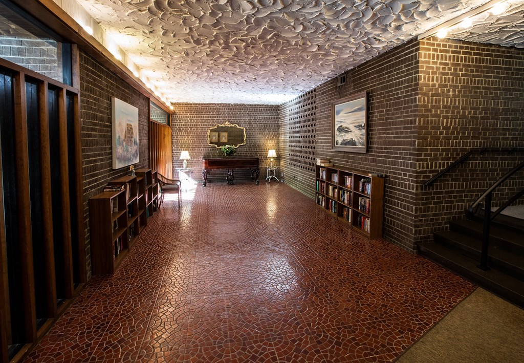 A hallway with a red tiled floor and brick walls.