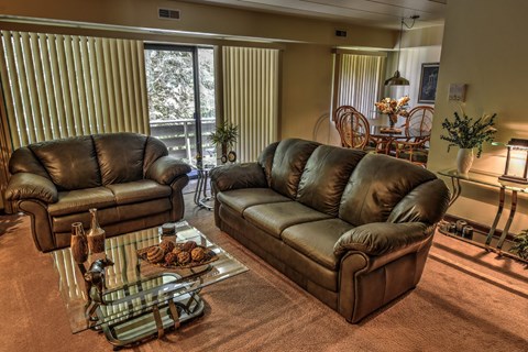 A living room with two brown leather sofas and a glass coffee table.
