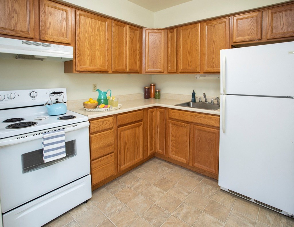 A kitchen with wooden cabinets and a white stove and refrigerator.