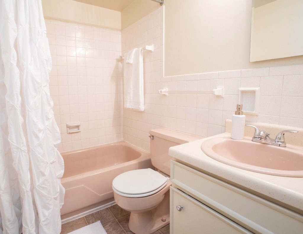 A white bathroom with a toilet, sink, and bathtub.
