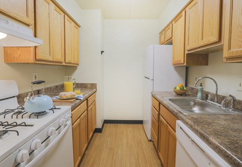 A kitchen with a white gas stove and wooden cabinets.