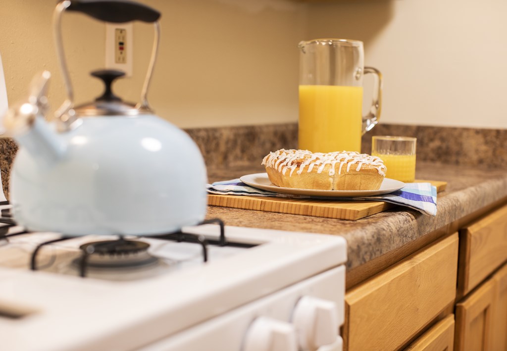 A blue tea kettle is on a white stove.
