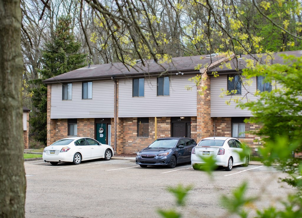 Three cars are parked in front of a brick building.