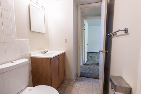 A white toilet sits in a bathroom next to a sink and a bathtub.