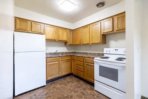 A kitchen with white appliances and wooden cabinets.