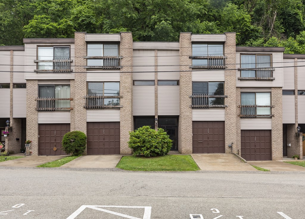 A building with brown doors and windows is surrounded by greenery.