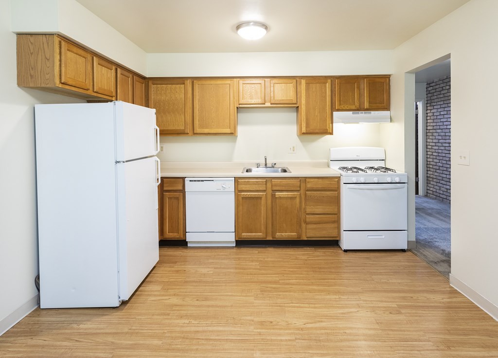 A kitchen with wooden cabinets and white appliances.