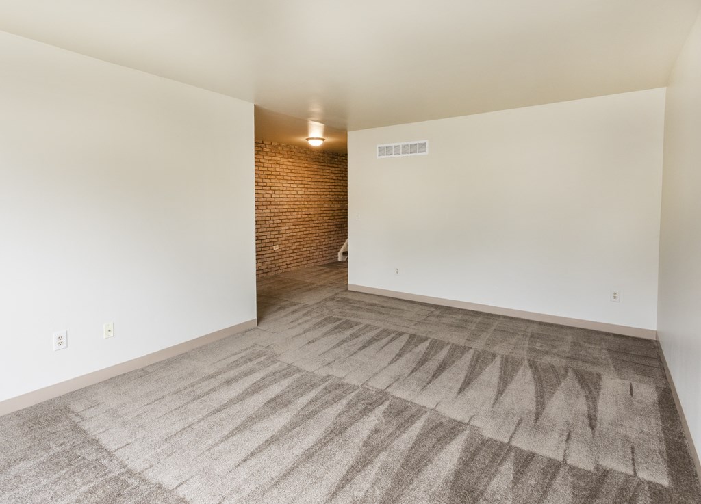 A room with a carpeted floor and a brick wall.