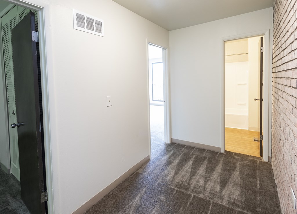 A room with a carpeted floor and a brick wall.