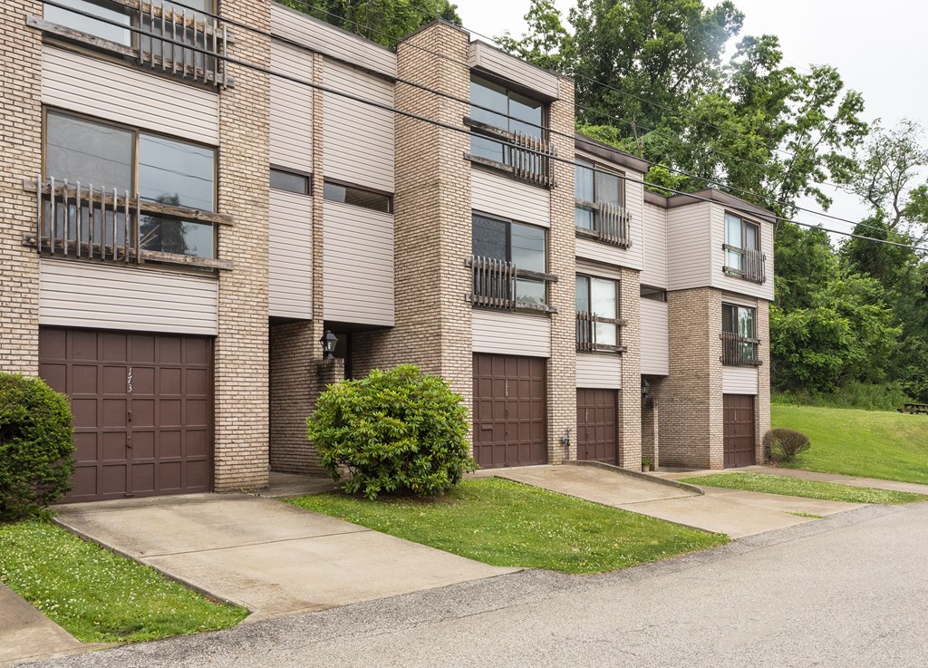 A row of brown brick apartment buildings with garages.
