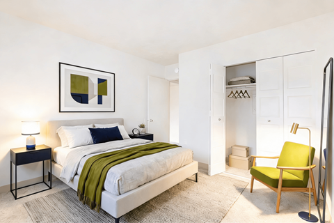 A bedroom with a bed, a chair, and a lamp.