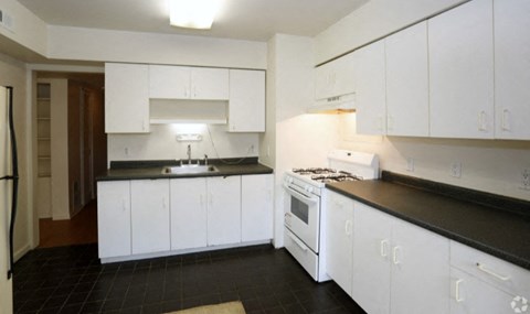 A kitchen with white cabinets and black countertops.