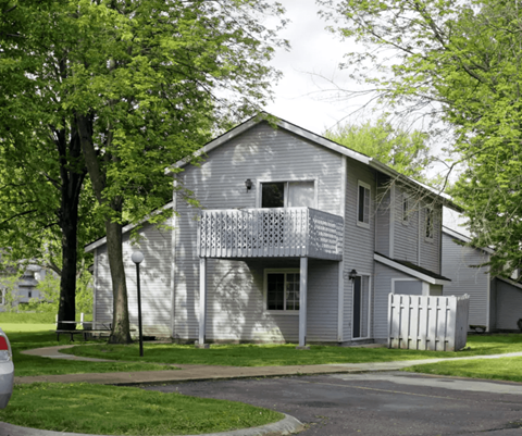 A grey house with a white picket fence in front.
