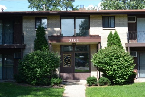 The front of apartment building number 3301 with bushes in front.