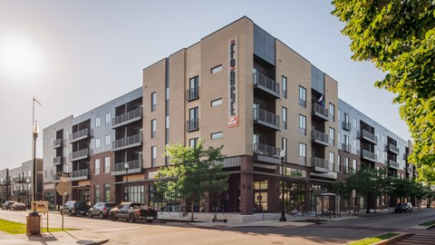 A modern apartment building with a parking lot in front.