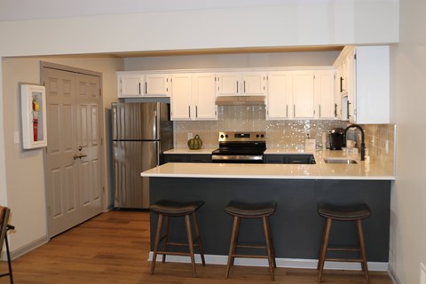 A kitchen with a white counter top and a refrigerator.