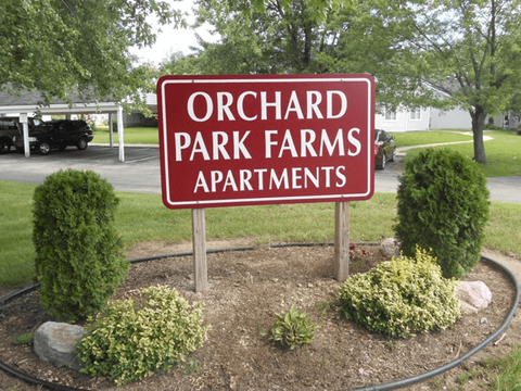 A sign for Orchard Park Farms Apartments is shown in front of a landscaped area.