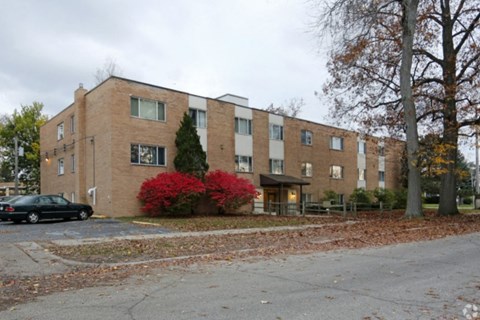 A black car is parked in front of a brick building.