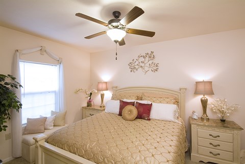 A bedroom with a bed, nightstands, and a ceiling fan.